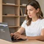 Femme dans la trentaine consultant les dernières nouveautés tech sur un ordinateur portable dans un bureau minimaliste moderne